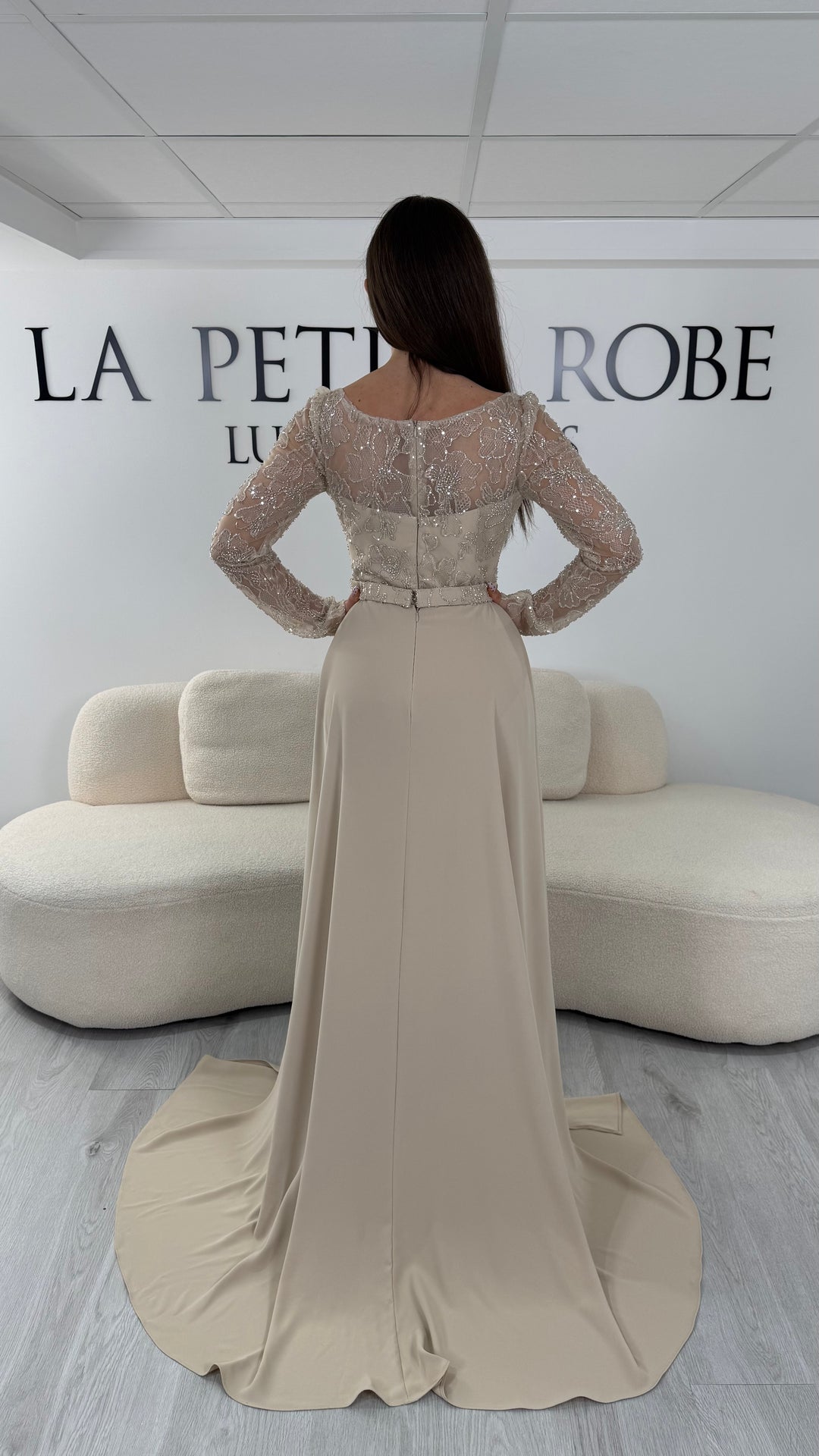Robe de soirée beige longue avec manches longues, col rond et traîne non amovible. Une robe élégante sans fente idéale pour cérémonie et soirée chic.