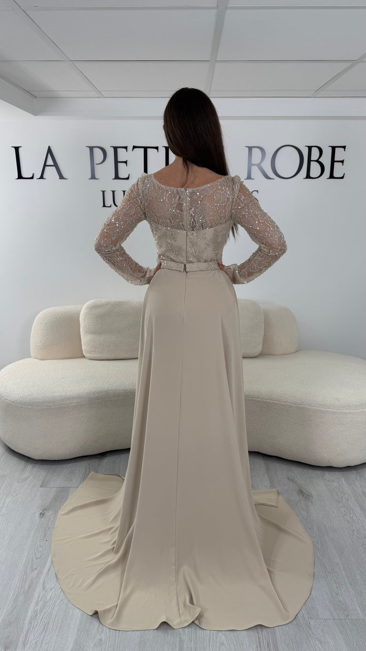 Robe de soirée beige longue avec manches longues, col rond et traîne non amovible. Une robe élégante sans fente idéale pour cérémonie et soirée chic.