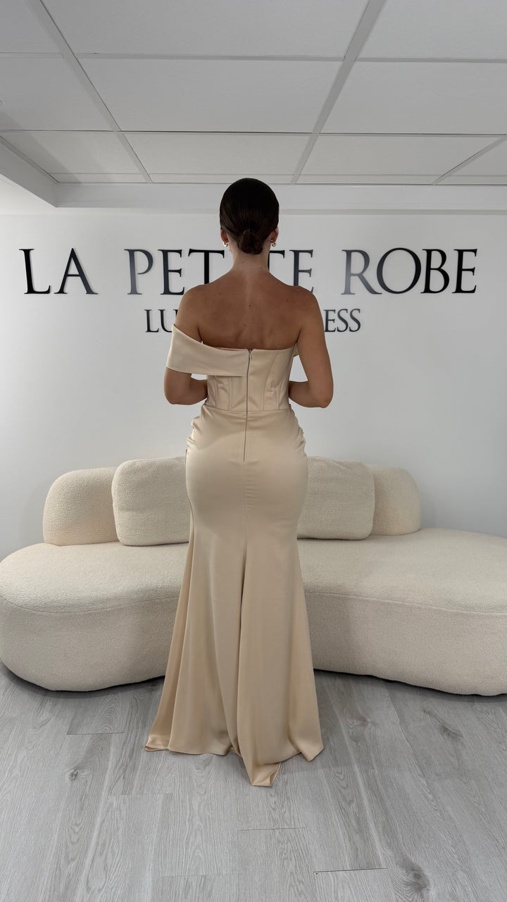Robe de soirée beige longue en satin avec col drapé asymétrique et coupe sans manches. Une robe élégante sans fente idéale pour mariage, gala et cérémonie.
