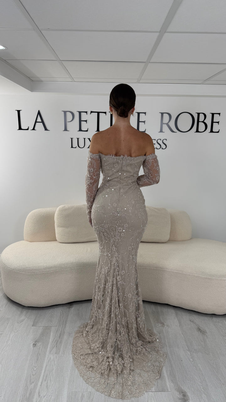 Robe de soirée taupe longue en dentelle et sequins avec col bardot et manches longues. Une robe élégante sans fente idéale pour mariage, gala et cérémonie.