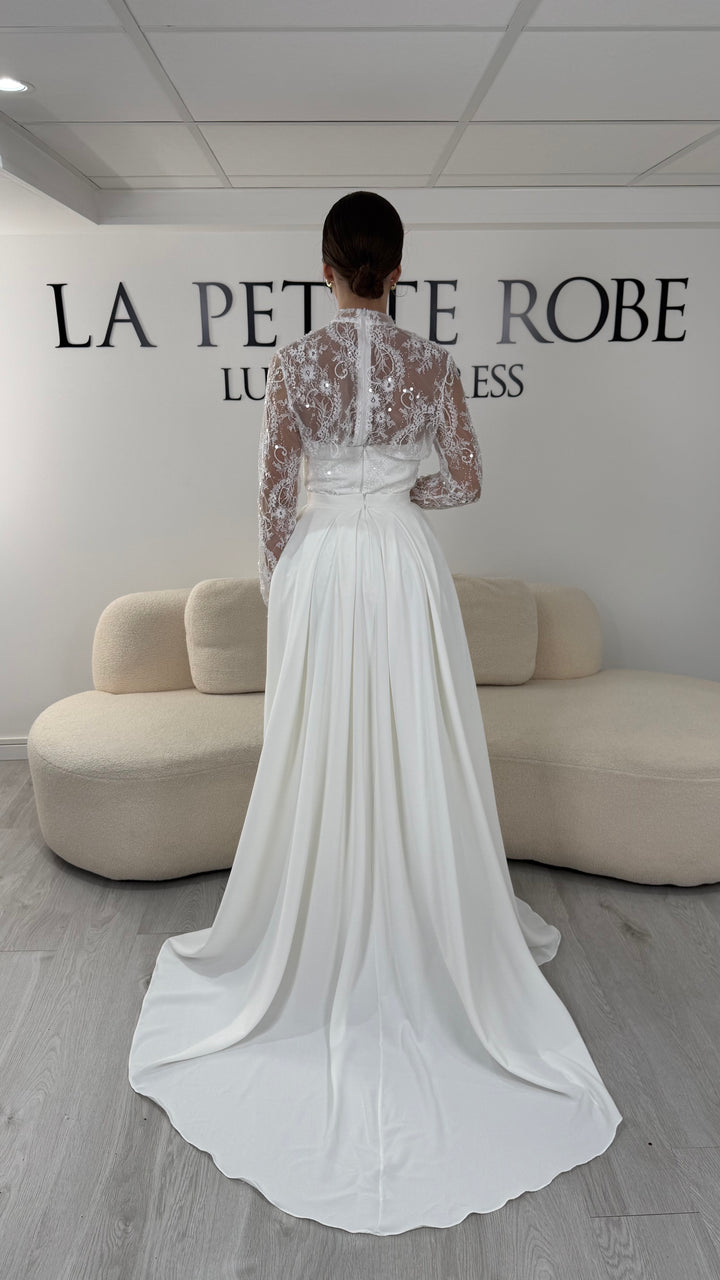 Robe de mariée blanche avec col montant en dentelle, manches longues, boléro amovible et traîne amovible. Une robe élégante sans fente idéale pour votre mariage.