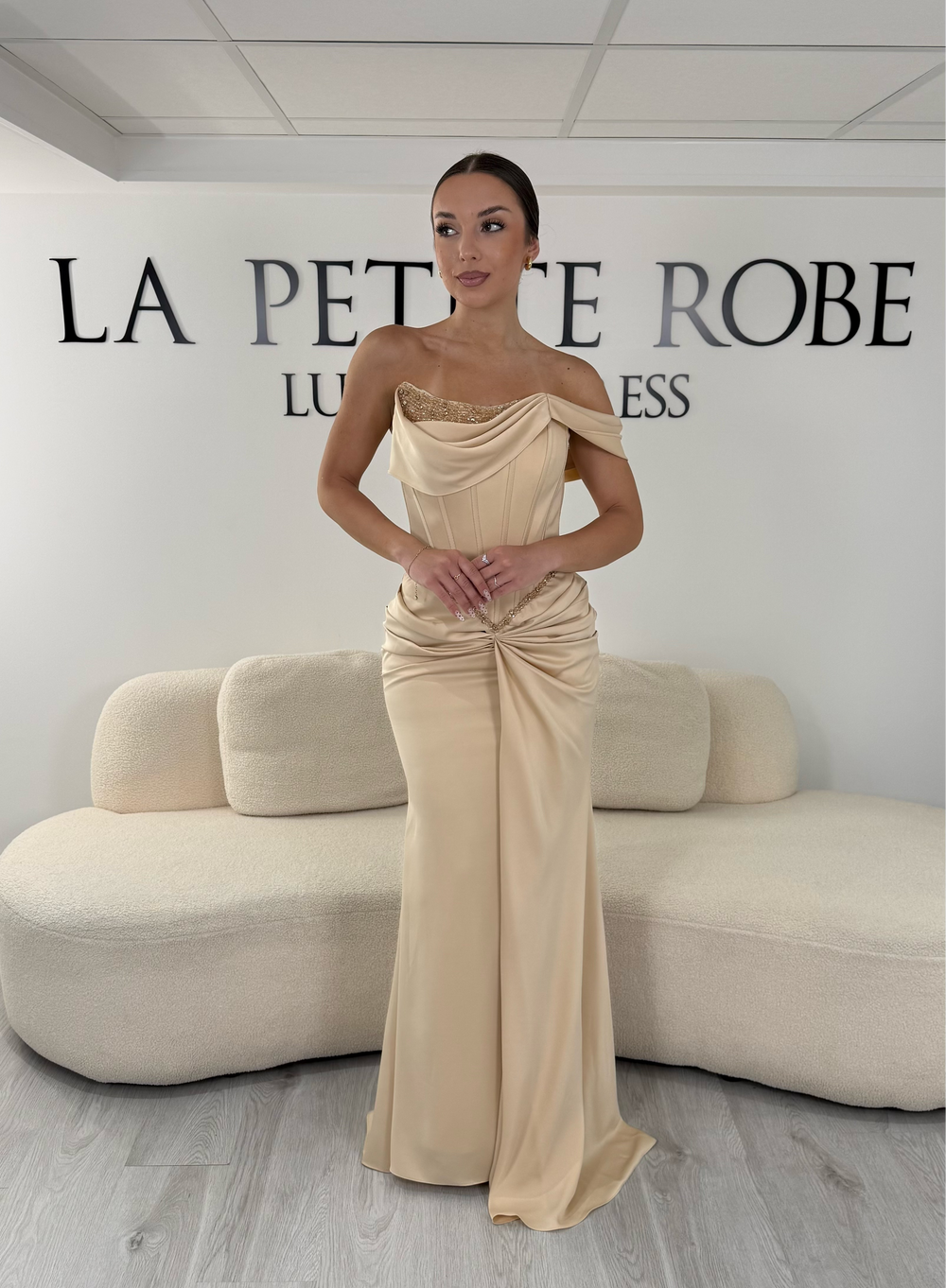 Robe de soirée beige longue en satin avec col drapé asymétrique et coupe sans manches. Une robe élégante sans fente idéale pour mariage, gala et cérémonie.