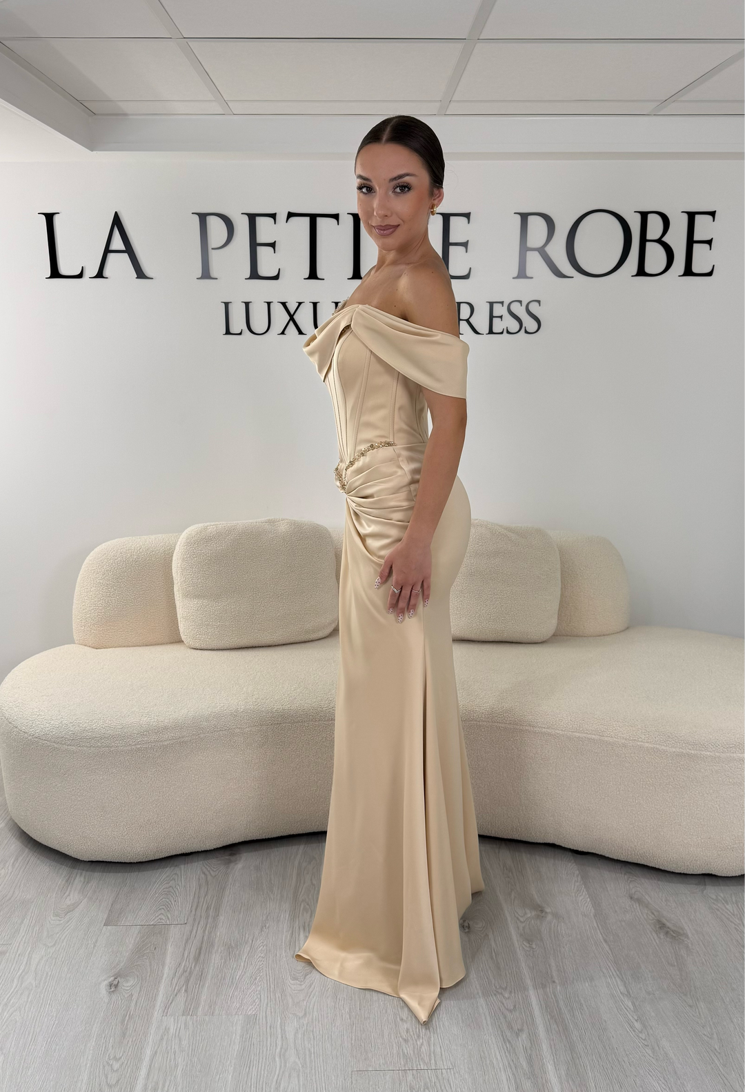 Robe de soirée beige longue en satin avec col drapé asymétrique et coupe sans manches. Une robe élégante sans fente idéale pour mariage, gala et cérémonie.