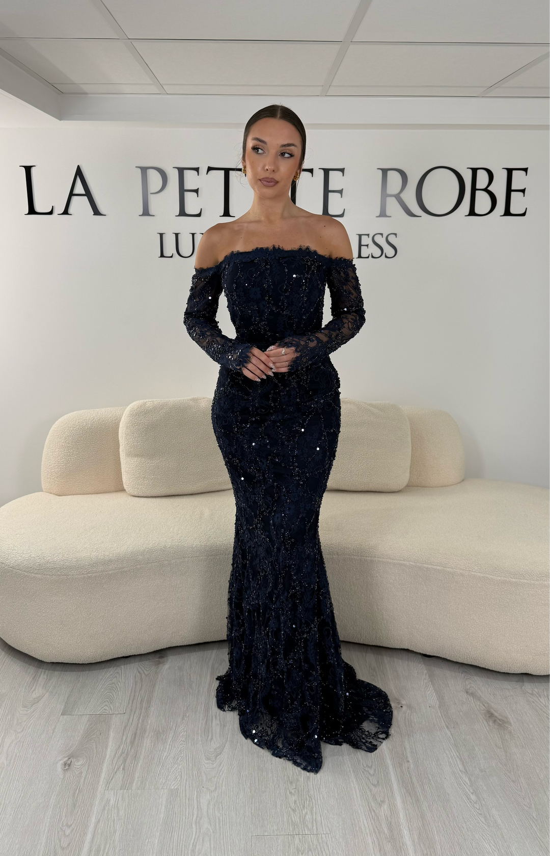 Robe de soirée bleu marine longue en dentelle et sequins avec col bardot et manches longues. Une robe élégante sans fente idéale pour mariage, gala et cérémonie.