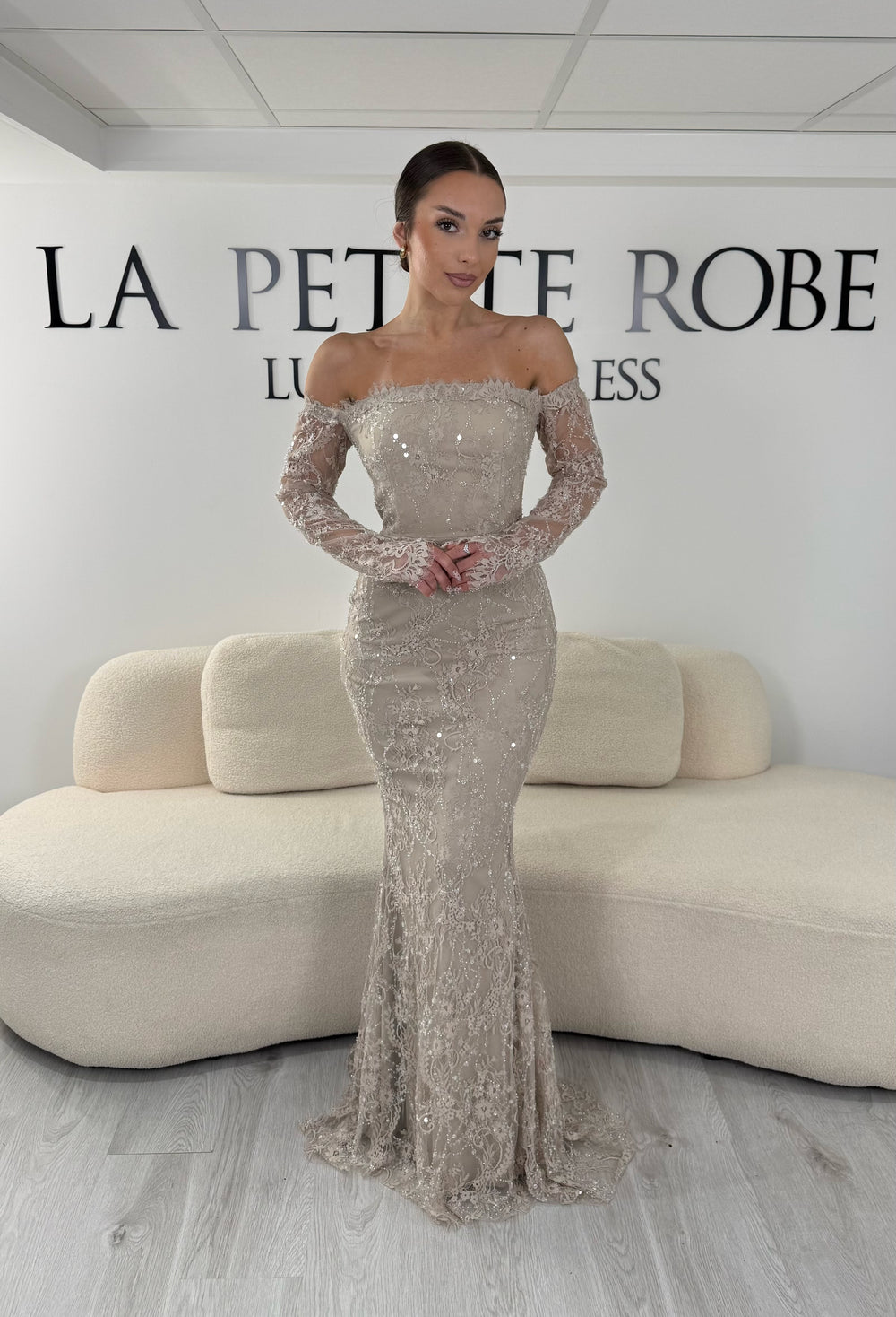 Robe de soirée taupe longue en dentelle et sequins avec col bardot et manches longues. Une robe élégante sans fente idéale pour mariage, gala et cérémonie.