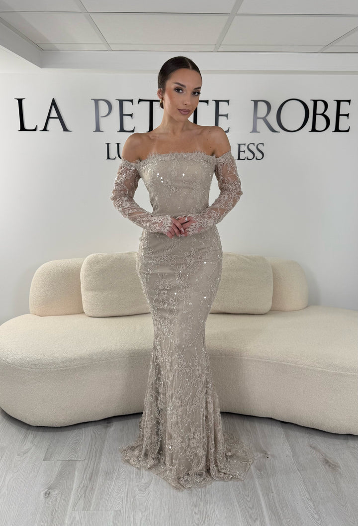 Robe de soirée taupe longue en dentelle et sequins avec col bardot et manches longues. Une robe élégante sans fente idéale pour mariage, gala et cérémonie.