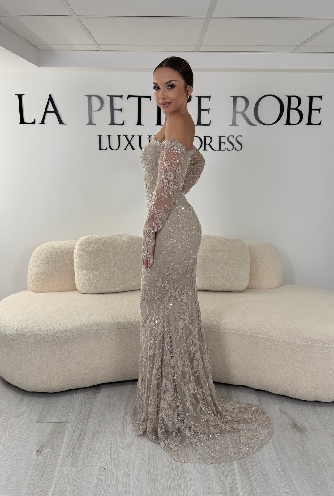Robe de soirée taupe longue en dentelle et sequins avec col bardot et manches longues. Une robe élégante sans fente idéale pour mariage, gala et cérémonie.