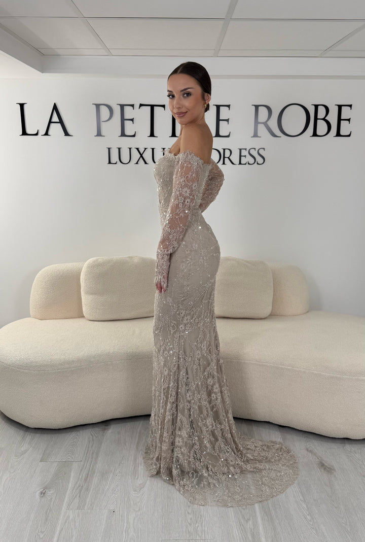 Robe de soirée taupe longue en dentelle et sequins avec col bardot et manches longues. Une robe élégante sans fente idéale pour mariage, gala et cérémonie.