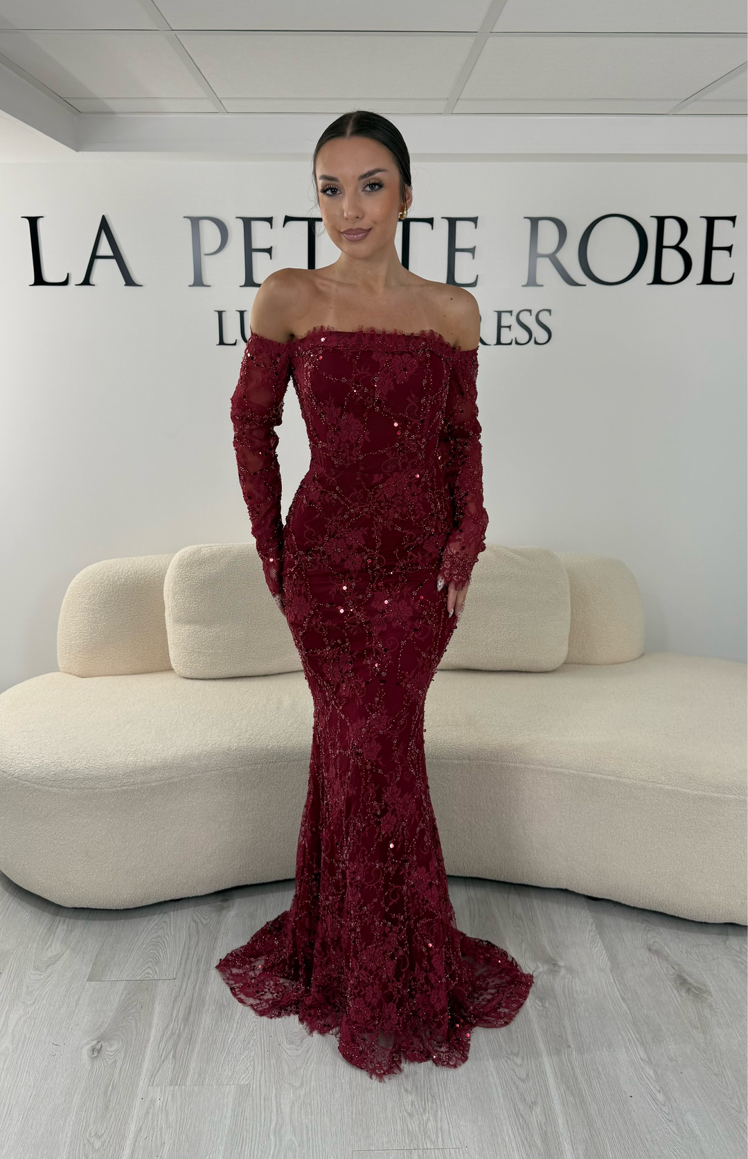 Robe de soirée bordeaux longue en dentelle et sequins avec col bardot et manches longues. Une robe élégante sans fente idéale pour mariage, gala et cérémonie.