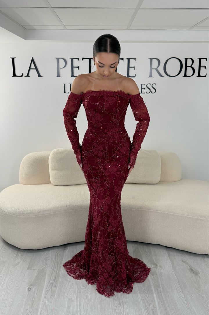 Robe de soirée bordeaux longue en dentelle et sequins avec col bardot et manches longues. Une robe élégante sans fente idéale pour mariage, gala et cérémonie.
