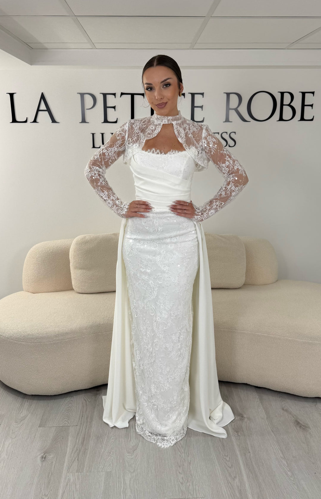 Robe de mariée blanche avec col montant en dentelle, manches longues, boléro amovible et traîne amovible. Une robe élégante sans fente idéale pour votre mariage.