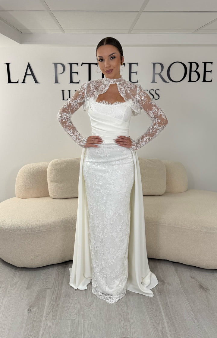 Robe de mariée blanche avec col montant en dentelle, manches longues, boléro amovible et traîne amovible. Une robe élégante sans fente idéale pour votre mariage.