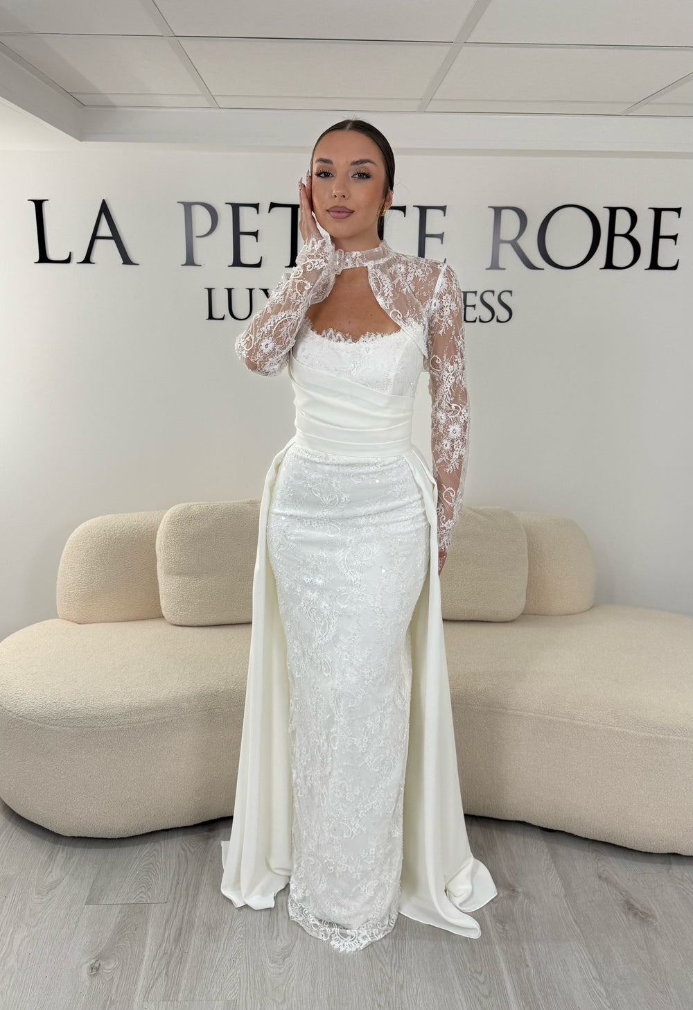 Robe de mariée blanche avec col montant en dentelle, manches longues, boléro amovible et traîne amovible. Une robe élégante sans fente idéale pour votre mariage.