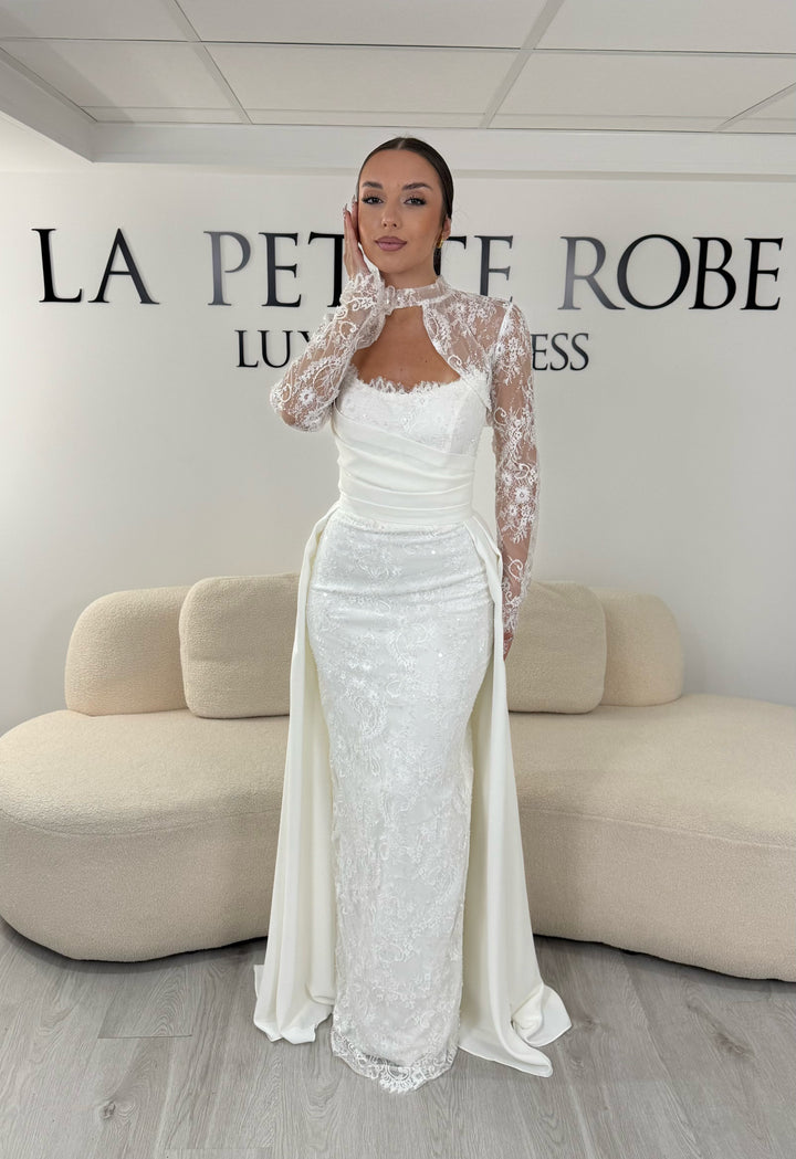 Robe de mariée blanche avec col montant en dentelle, manches longues, boléro amovible et traîne amovible. Une robe élégante sans fente idéale pour votre mariage.