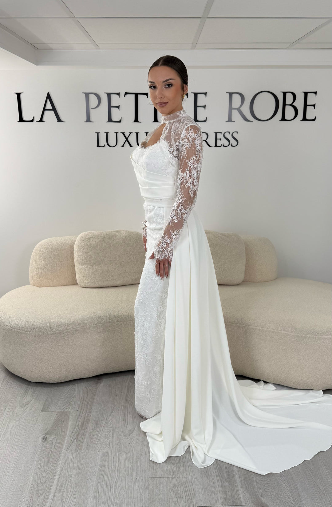 Robe de mariée blanche avec col montant en dentelle, manches longues, boléro amovible et traîne amovible. Une robe élégante sans fente idéale pour votre mariage.