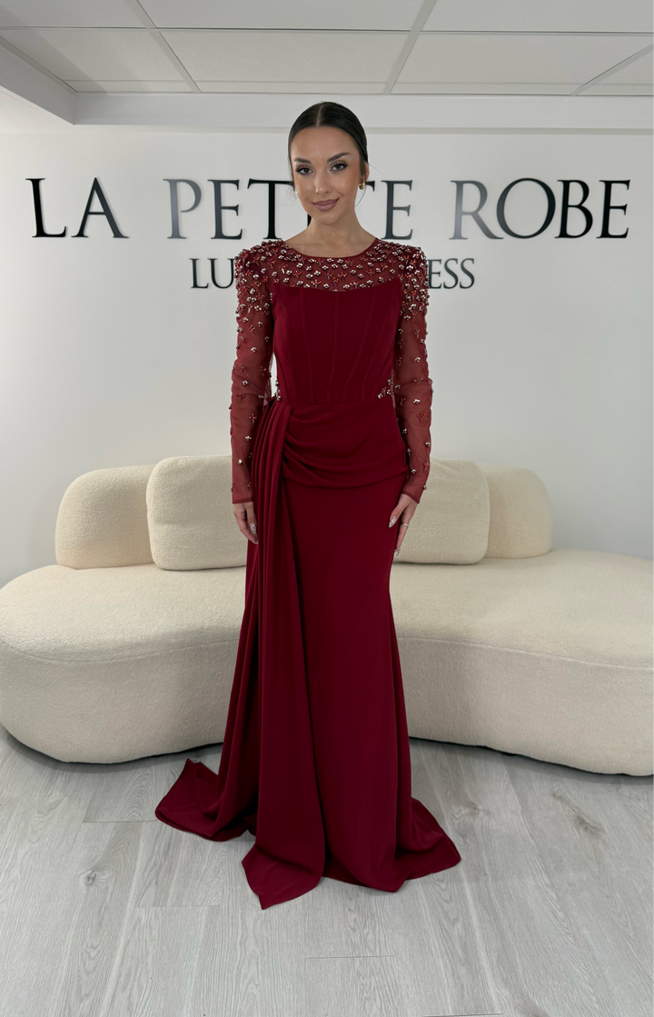 Robe de soirée bordeaux longue avec col rond, manches longues brodées et détails perlés. Une robe élégante avec fente, idéale pour mariage, gala et cérémonie.
