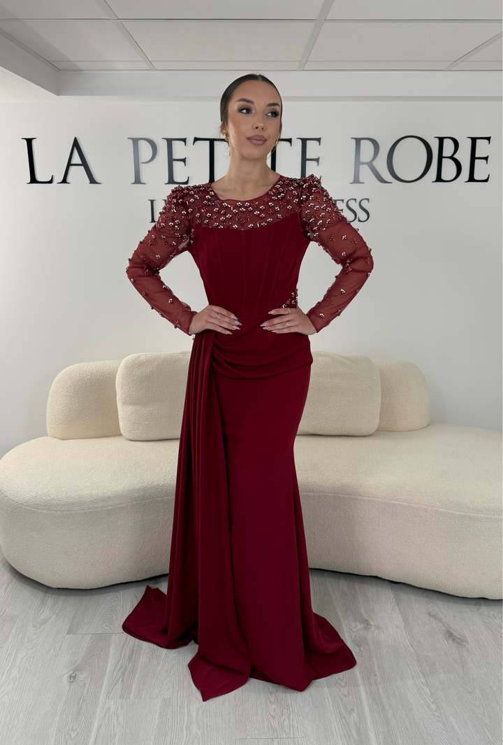 Robe de soirée bordeaux longue avec col rond, manches longues brodées et détails perlés. Une robe élégante avec fente, idéale pour mariage, gala et cérémonie.