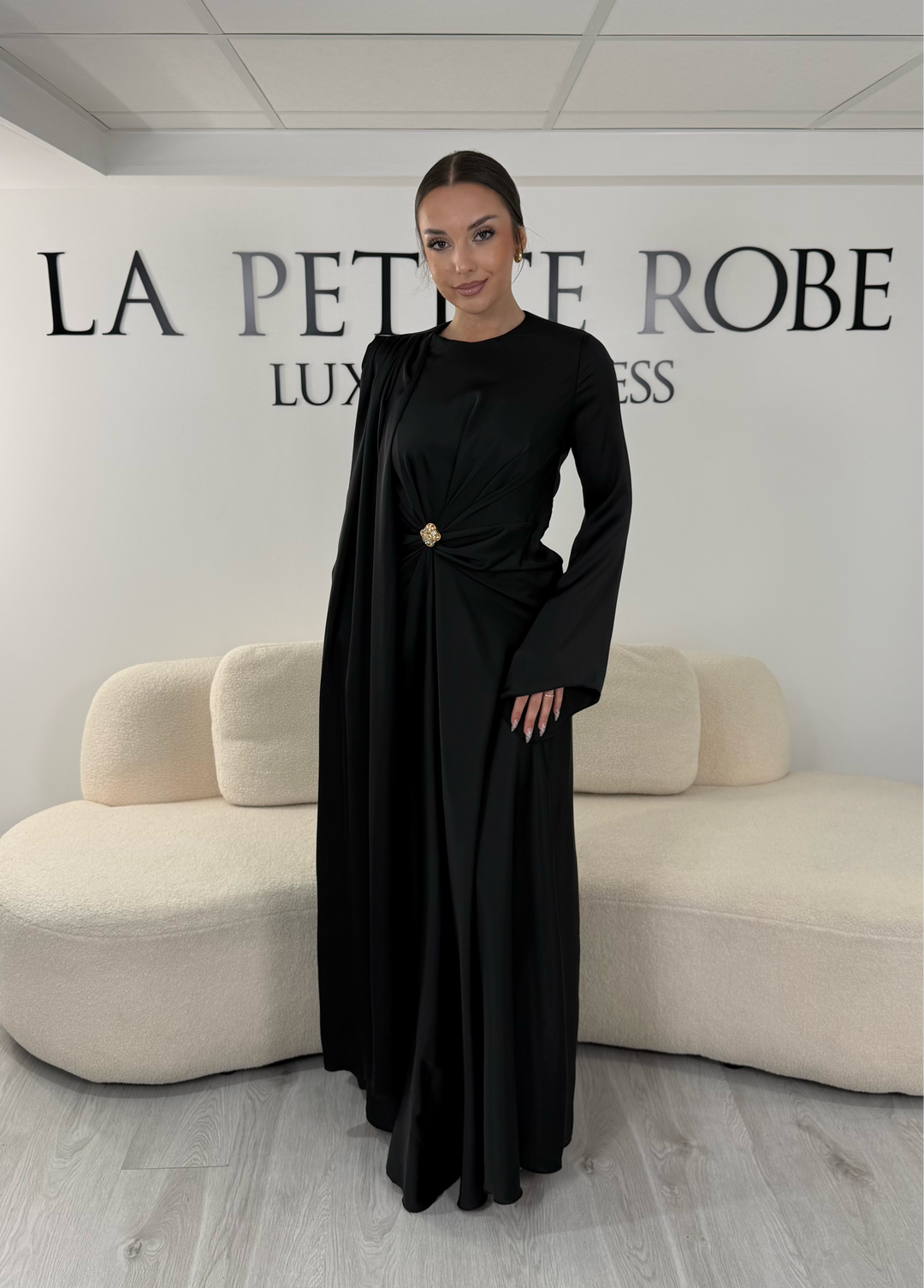 Robe de soirée modeste noire longue avec col rond, manches longues et drapé élégant. Une robe sans fente idéale pour mariage, cérémonie ou demoiselle d'honneur.