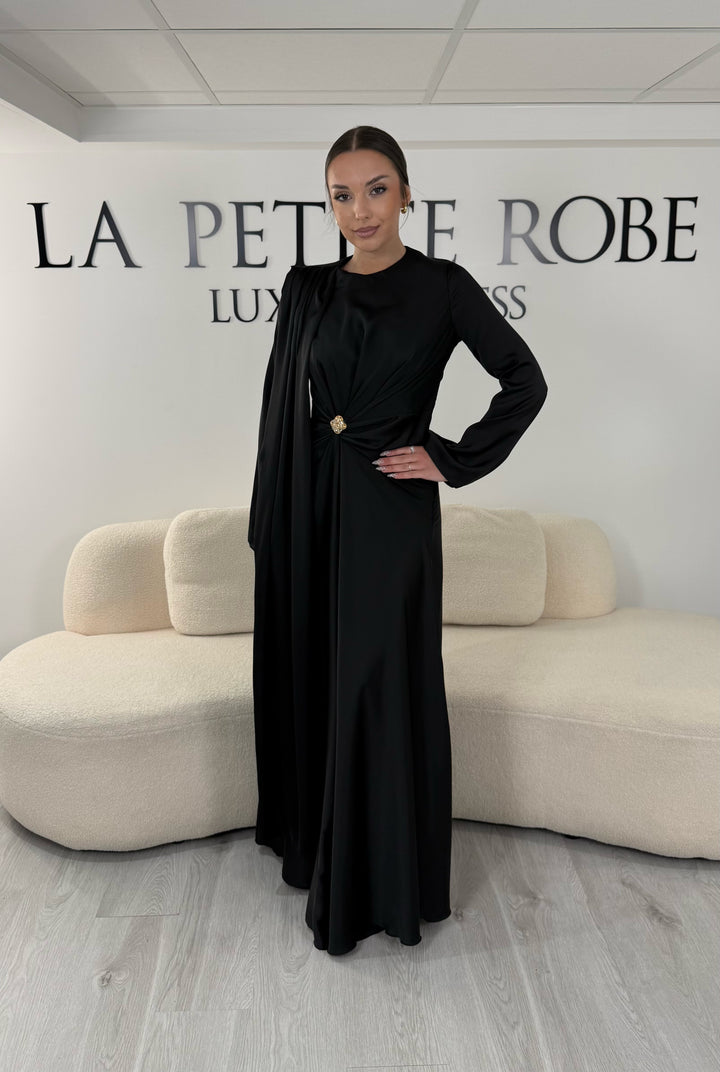 Robe de soirée modeste noire longue avec col rond, manches longues et drapé élégant. Une robe sans fente idéale pour mariage, cérémonie ou demoiselle d'honneur.