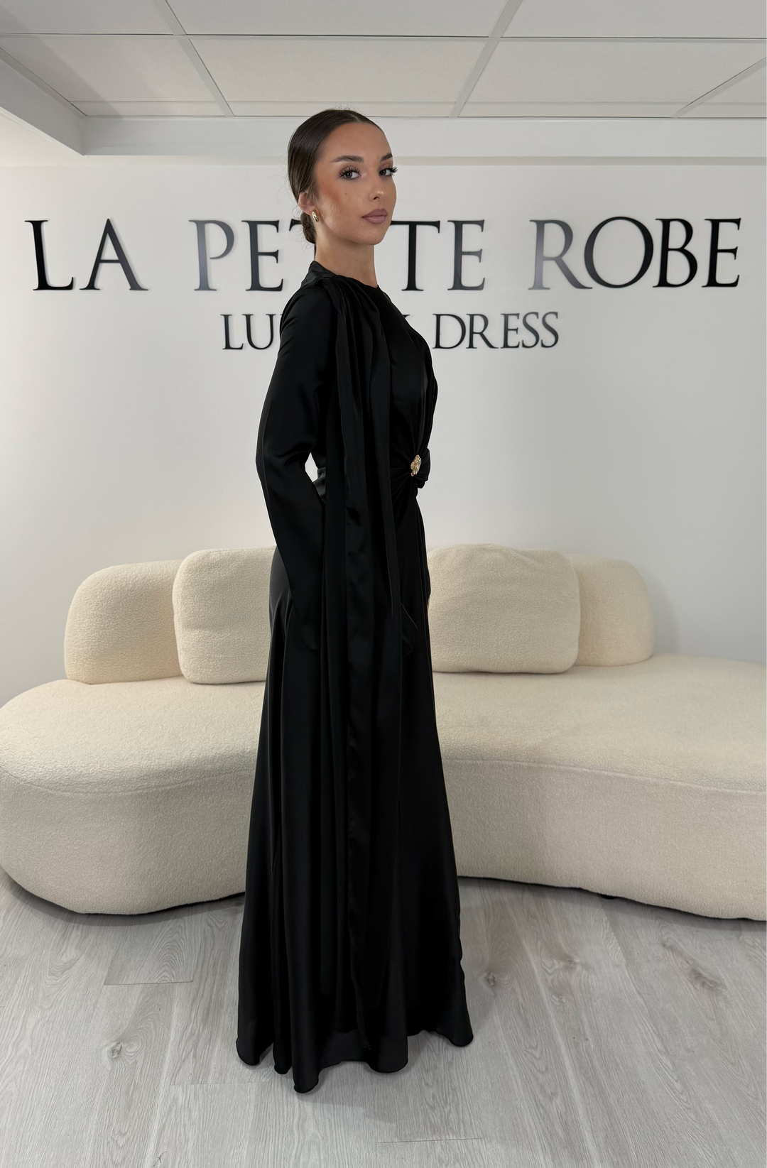 Robe de soirée modeste noire longue avec col rond, manches longues et drapé élégant. Une robe sans fente idéale pour mariage, cérémonie ou demoiselle d'honneur.
