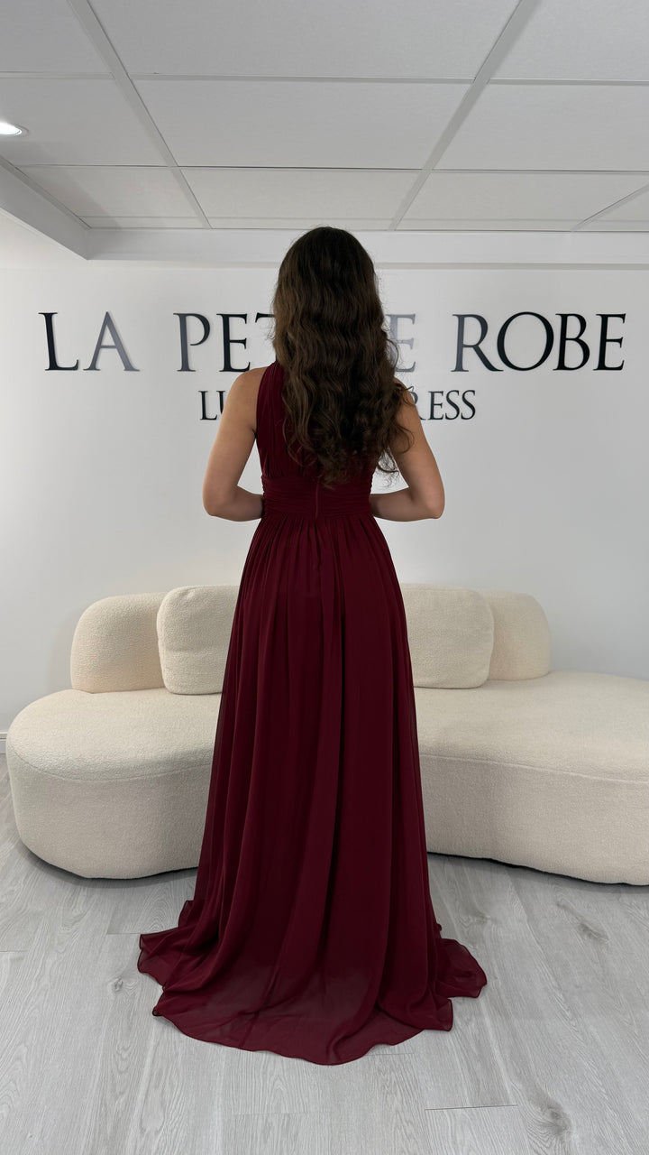 Découvrez cette robe de soirée bordeaux longue et fluide. Sans manche, avec col montant drapé et sans fente, elle offre une allure élégante et raffinée pour toutes vos occasions.
