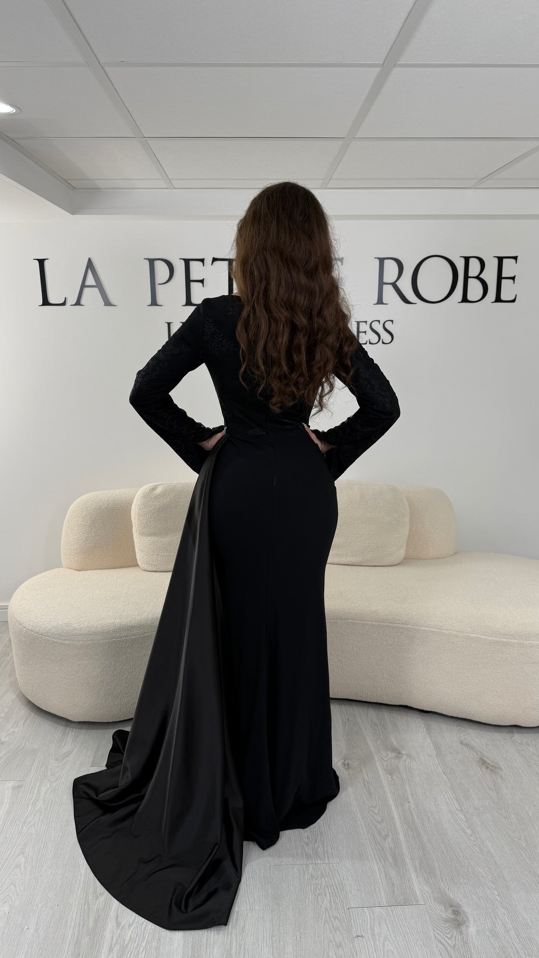 Découvrez cette robe de soirée noire avec col bateau, manches longues et élégante traîne sur le côté. Une robe sans fente, parfaite pour une allure raffinée et sophistiquée.