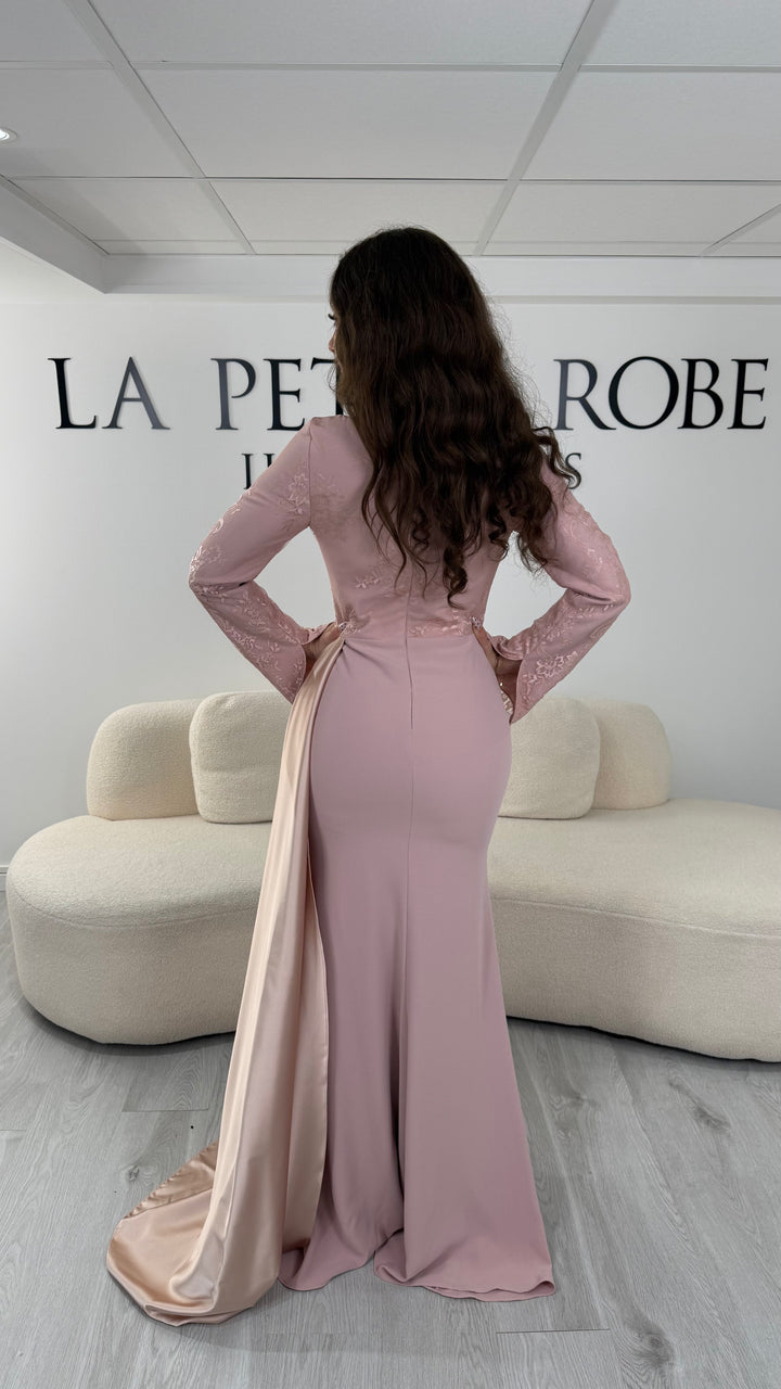 Découvrez cette robe de soirée rose avec col rond, manches longues en dentelle et élégante traîne sur le côté. Une robe sans fente, parfaite pour une allure raffinée.