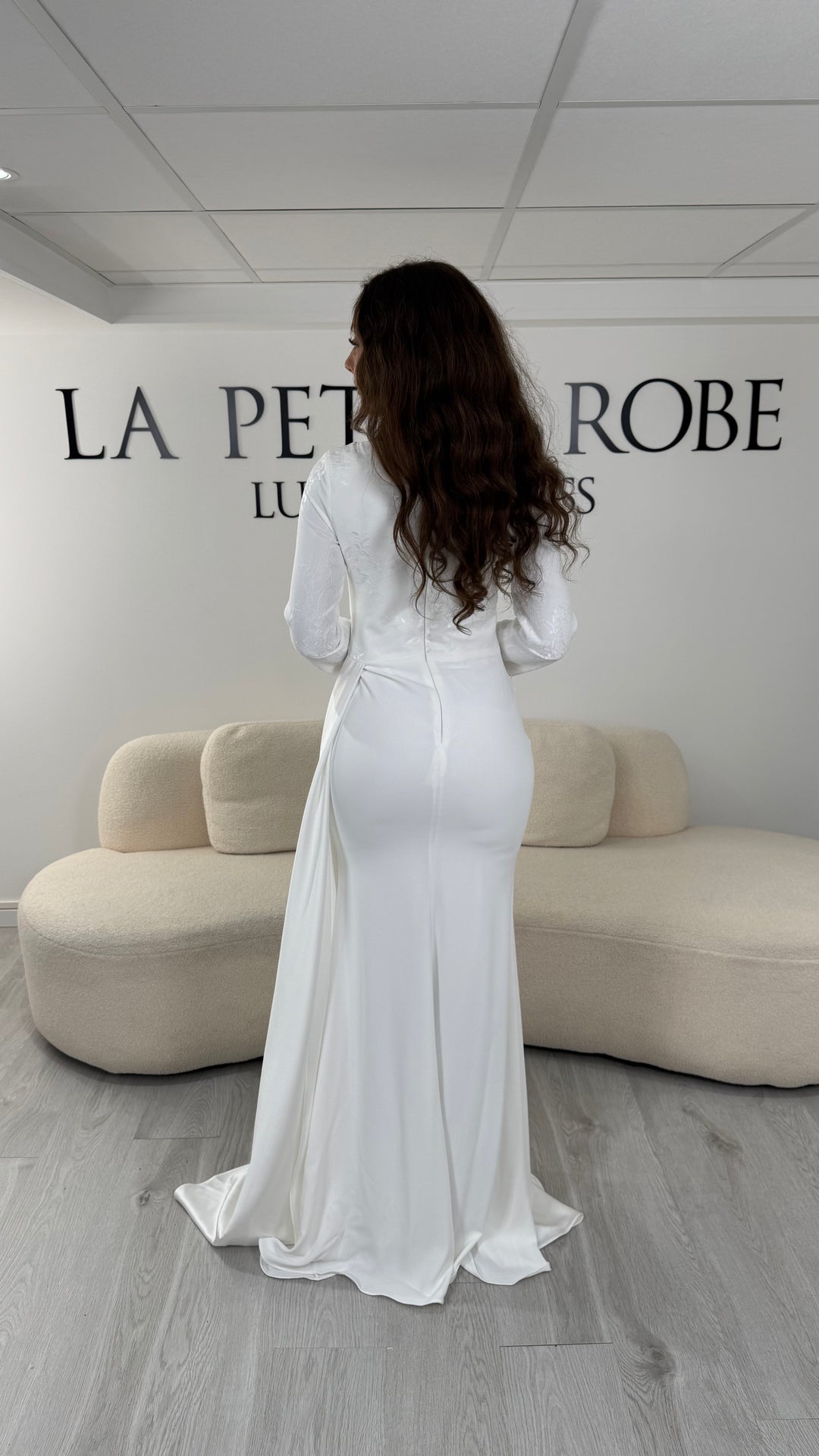Découvrez cette robe de mariée blanche avec col rond, manches longues en dentelle et élégante traîne sur le côté. Une création raffinée sans fente pour un mariage inoubliable.