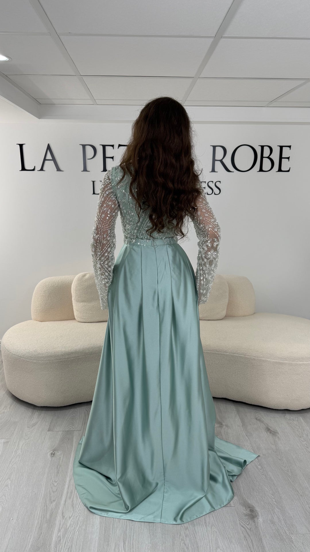 Découvrez cette robe de soirée vert d'eau avec col carré, manches longues brodées et traîne amovible. Une robe élégante sans fente, parfaite pour vos plus belles occasions.