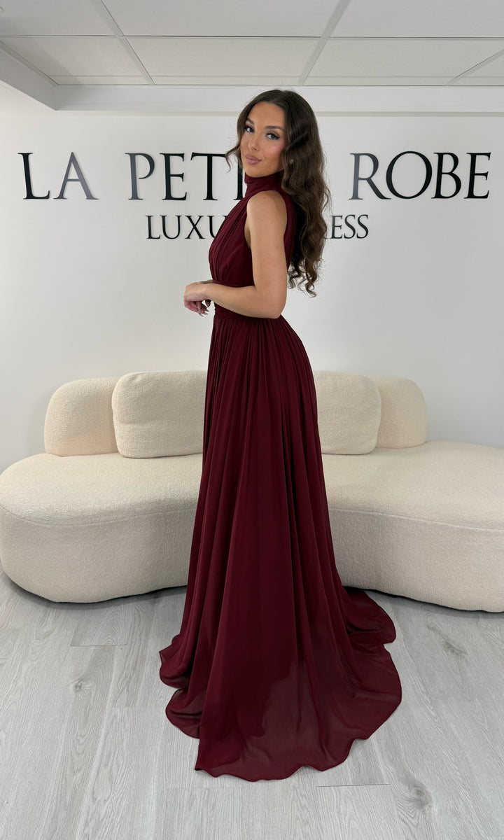 Découvrez cette robe de soirée bordeaux longue et fluide. Sans manche, avec col montant drapé et sans fente, elle offre une allure élégante et raffinée pour toutes vos occasions.