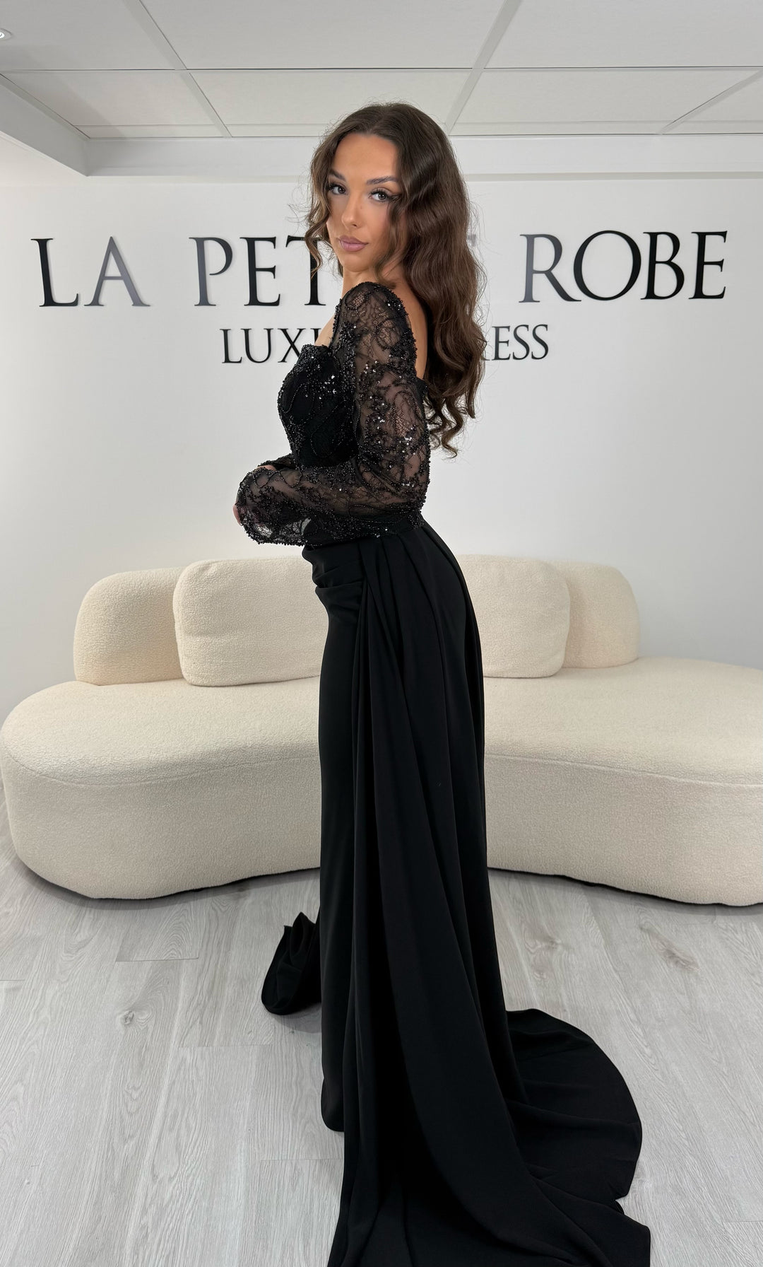 Découvrez cette robe de soirée noire avec col carré, manches longues et traîne amovible. Une robe élégante sans fente, parfaite pour une allure chic et raffinée.