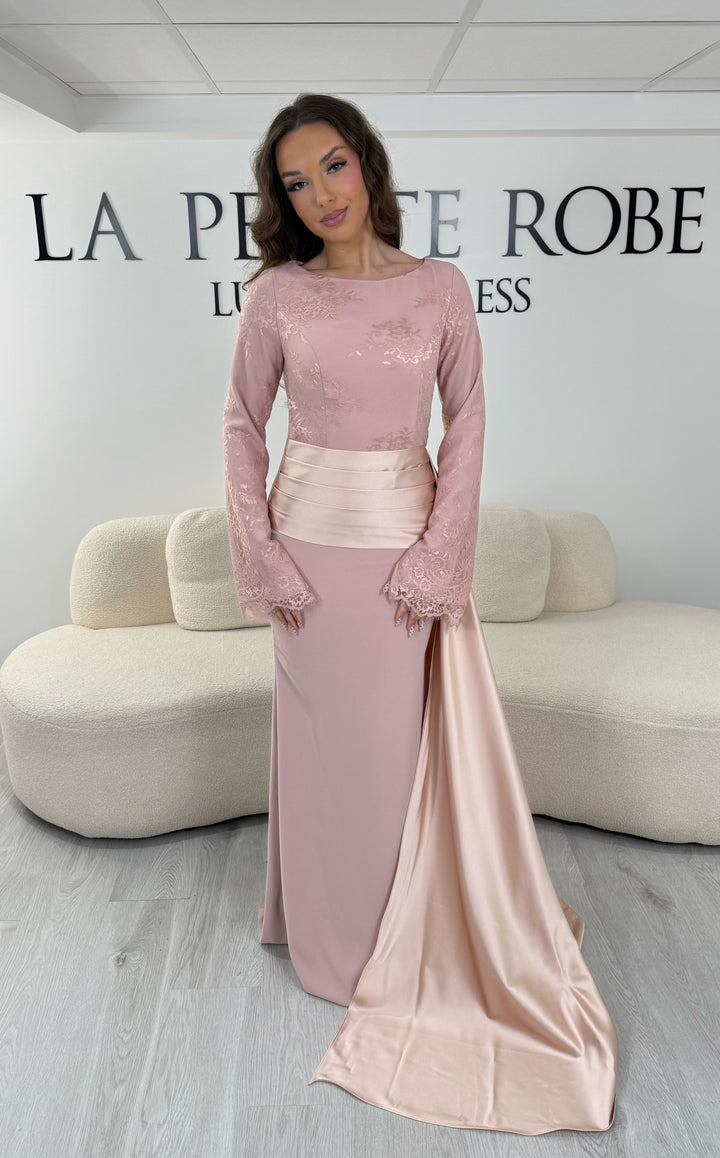 Découvrez cette robe de soirée rose avec col rond, manches longues en dentelle et élégante traîne sur le côté. Une robe sans fente, parfaite pour une allure raffinée.