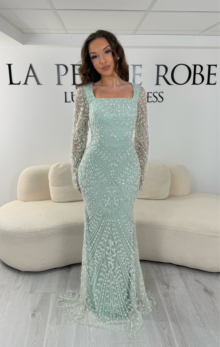 Découvrez cette robe de soirée vert d'eau avec col carré, manches longues brodées et traîne amovible. Une robe élégante sans fente, parfaite pour vos plus belles occasions.