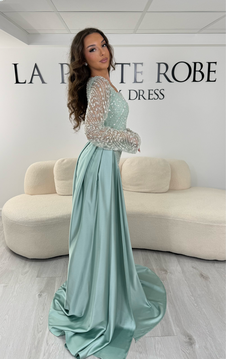 Découvrez cette robe de soirée vert d'eau avec col carré, manches longues brodées et traîne amovible. Une robe élégante sans fente, parfaite pour vos plus belles occasions.