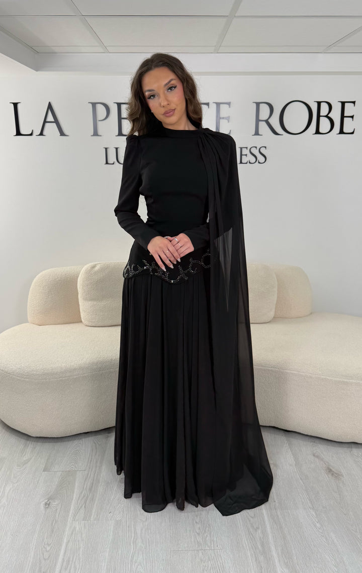 Découvrez cette robe de soirée noire avec col montant, manches longues et voile fluide intégré. Une robe élégante sans fente, parfaite pour mariage, gala et cérémonie.