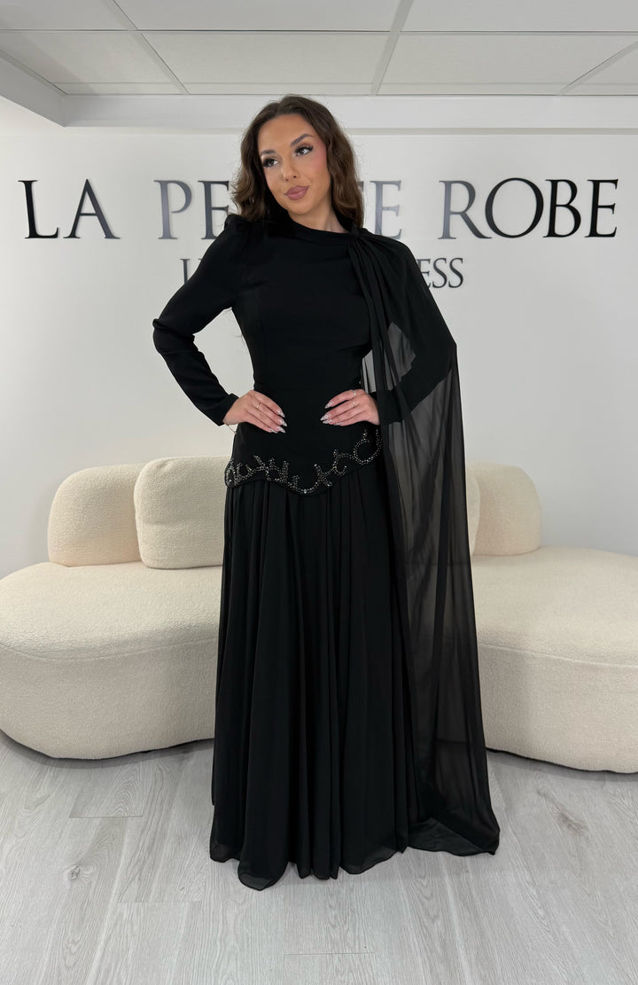 Découvrez cette robe de soirée noire avec col montant, manches longues et voile fluide intégré. Une robe élégante sans fente, parfaite pour mariage, gala et cérémonie.