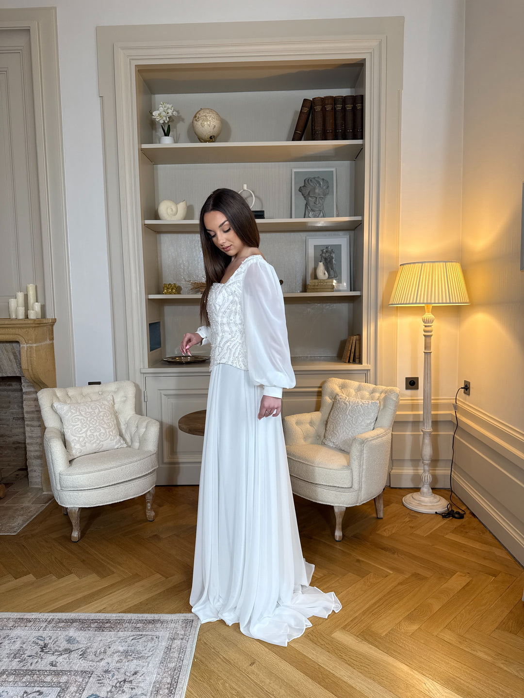 Longue robe de mariée blanche élégante à manches longues, col carré et coupe fluide sans fente. Une robe raffinée pour un mariage chic.