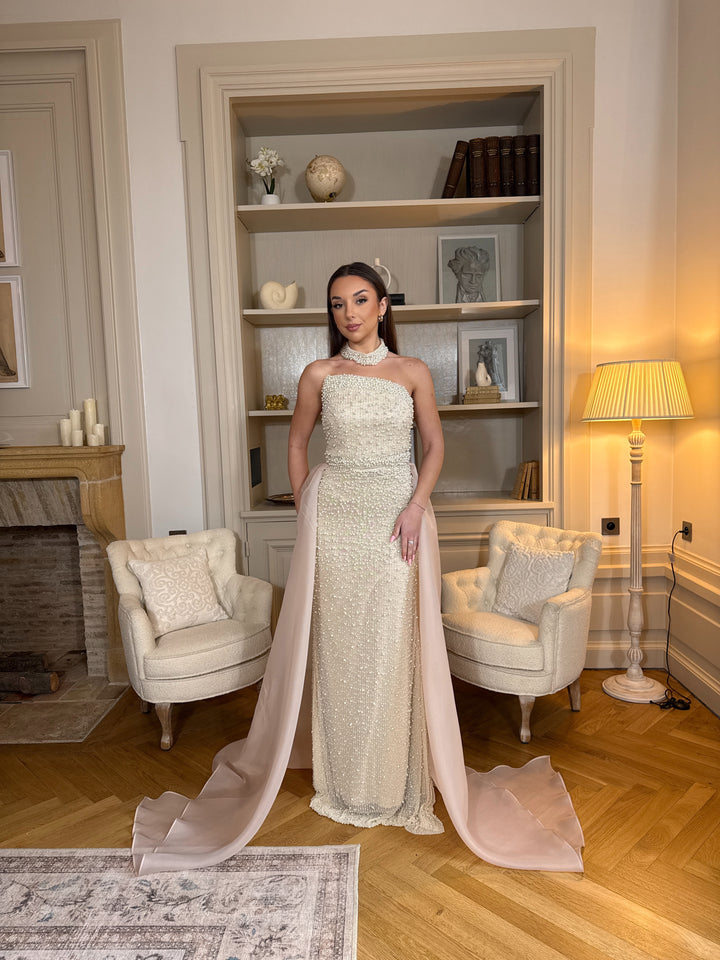 Longue robe de soirée beige élégante, col bustier sans manches, coupe fluide sans fente. Une robe raffinée pour vos soirées chic.