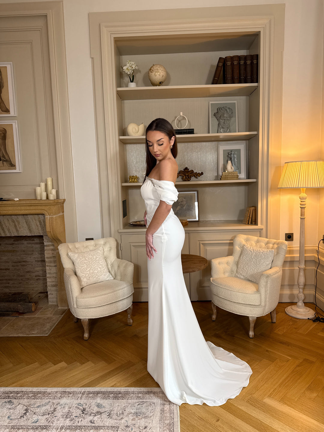 Robe de mariée blanche élégante au col bateau, coupe fluide sans fente. Une robe raffinée et intemporelle pour un mariage chic.