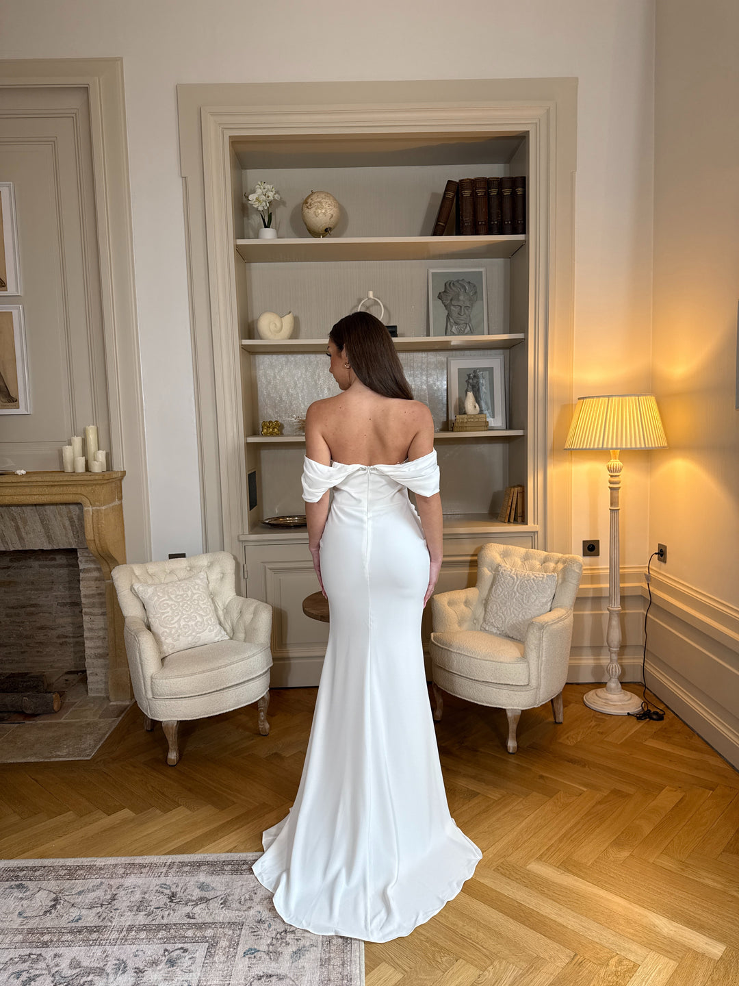 Robe de mariée blanche élégante au col bateau, coupe fluide sans fente. Une robe raffinée et intemporelle pour un mariage chic.