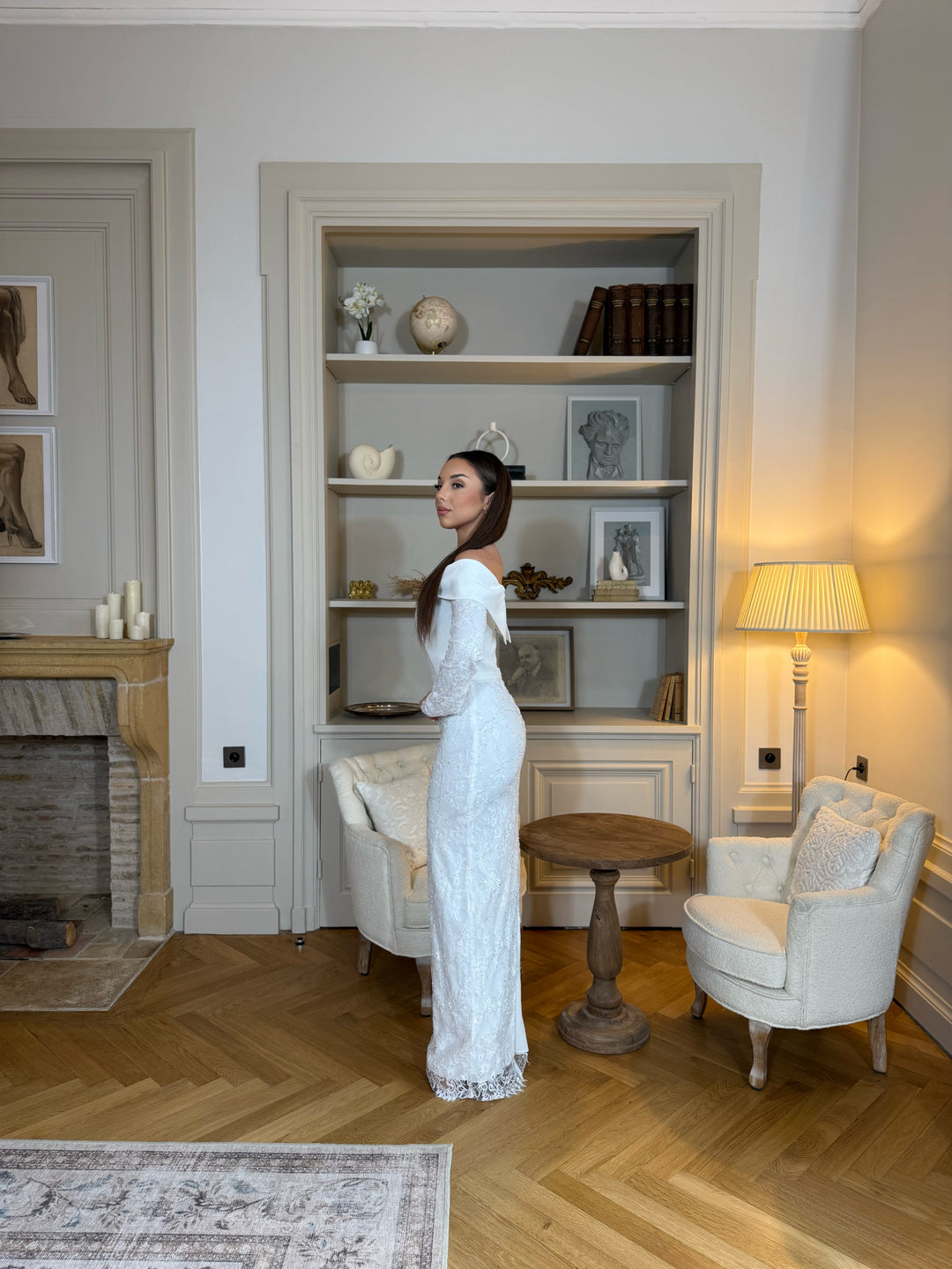 Robe de cérémonie blanche élégante avec col bateau, manches longues et fente à l’arrière. Une robe raffinée pour vos événements.