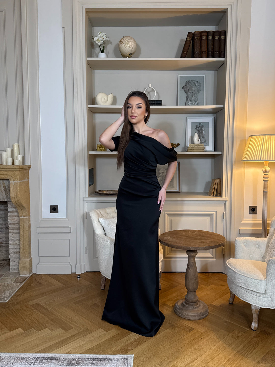 Robe de soirée noire chic au col asymétrique, sans manches et sans fente. Une robe élégante et moderne pour vos soirées raffinées.
