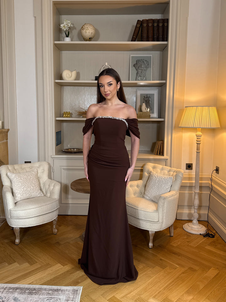 Robe de soirée marron élégante au col bateau, coupe longue et fluide sans fente. Une tenue chic et raffinée pour vos soirées.