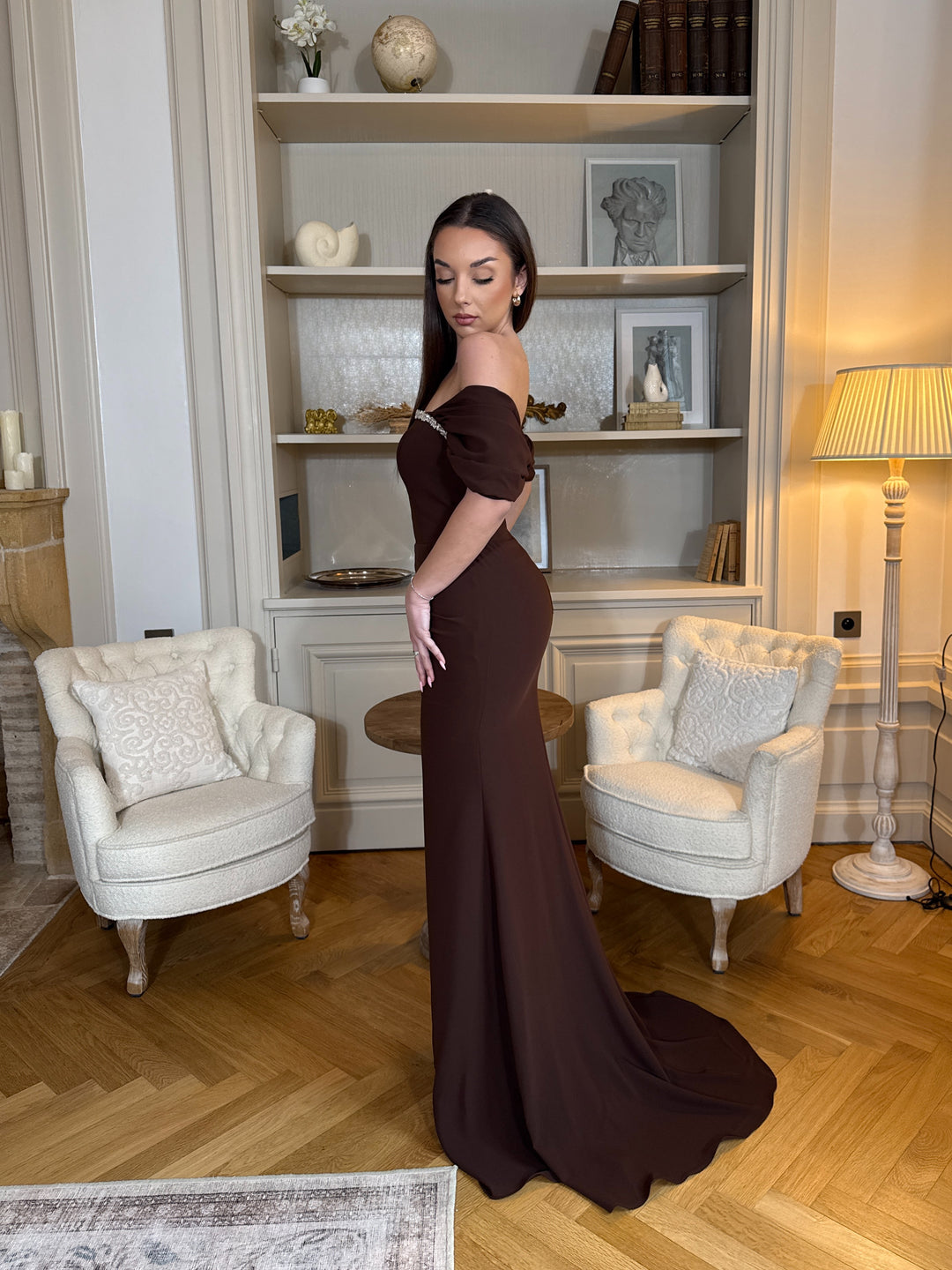 Robe de soirée marron élégante au col bateau, coupe longue et fluide sans fente. Une tenue chic et raffinée pour vos soirées.