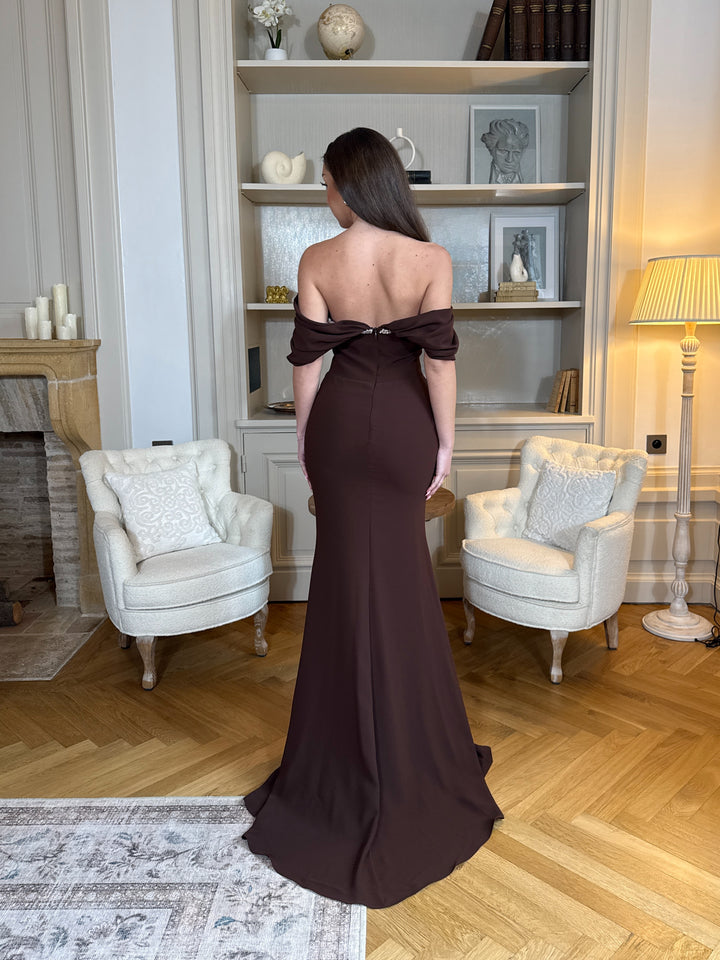 Robe de soirée marron élégante au col bateau, coupe longue et fluide sans fente. Une tenue chic et raffinée pour vos soirées.