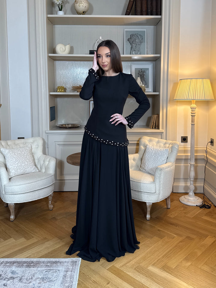 Robe de soirée élégante noire, coupe longue et fluide, col bateau chic et manches longues. Idéale pour mariage, gala et événements raffinés.