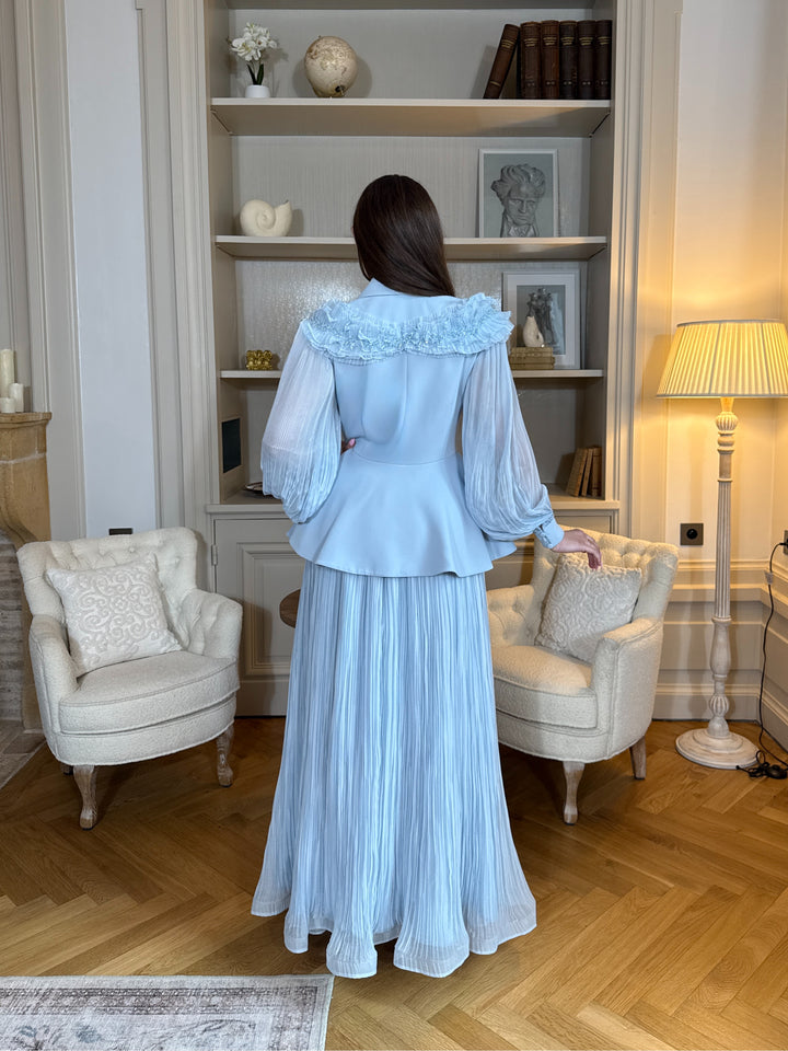 Ensemble blazer avec jupe bleu chic, manches longues plissées et détails floraux. Élégant, fluide et raffiné, parfait pour mariage ou cérémonie.