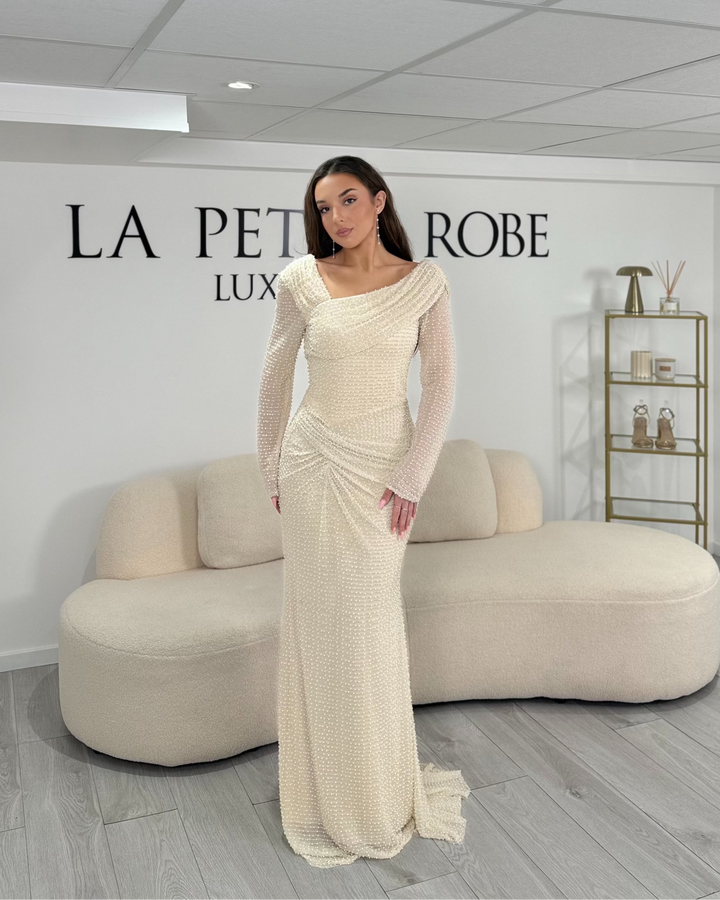 Robe de soirée élégante beige longue et fluide. Col bateau, manches longues, sans fente. Idéale pour mariage, gala ou soirée chic.