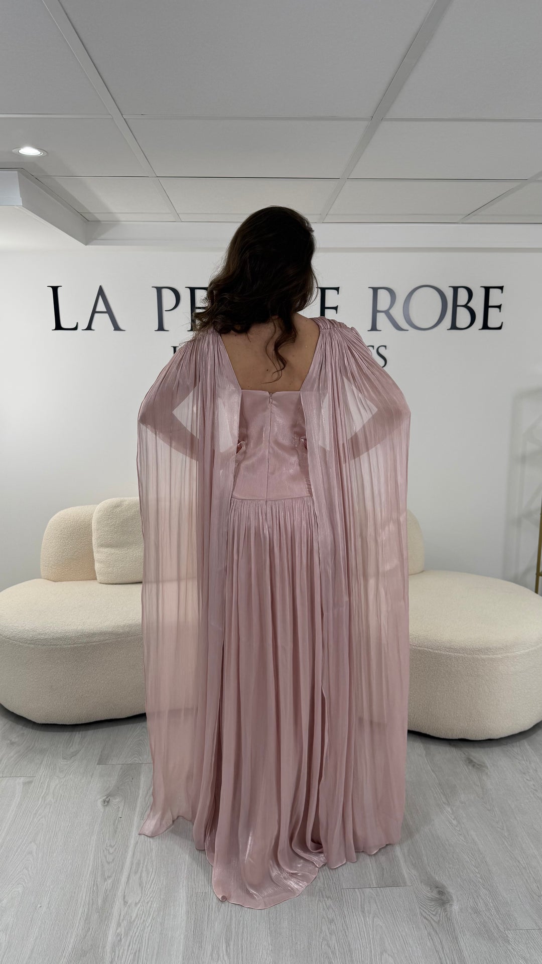 Robe de soirée rose élégante longue, col en V drapé, sans manche et dotée d’une fente raffinée. Coupe fluide et féminine idéale pour mariages et cérémonies.