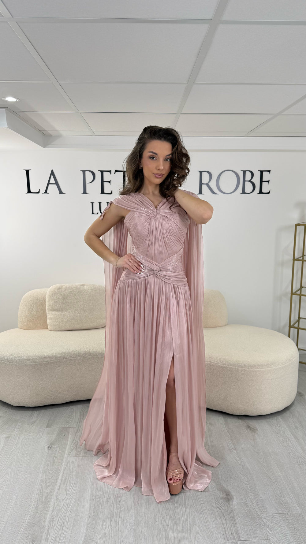 Robe de soirée rose élégante longue, col en V drapé, sans manche et dotée d’une fente raffinée. Coupe fluide et féminine idéale pour mariages et cérémonies.